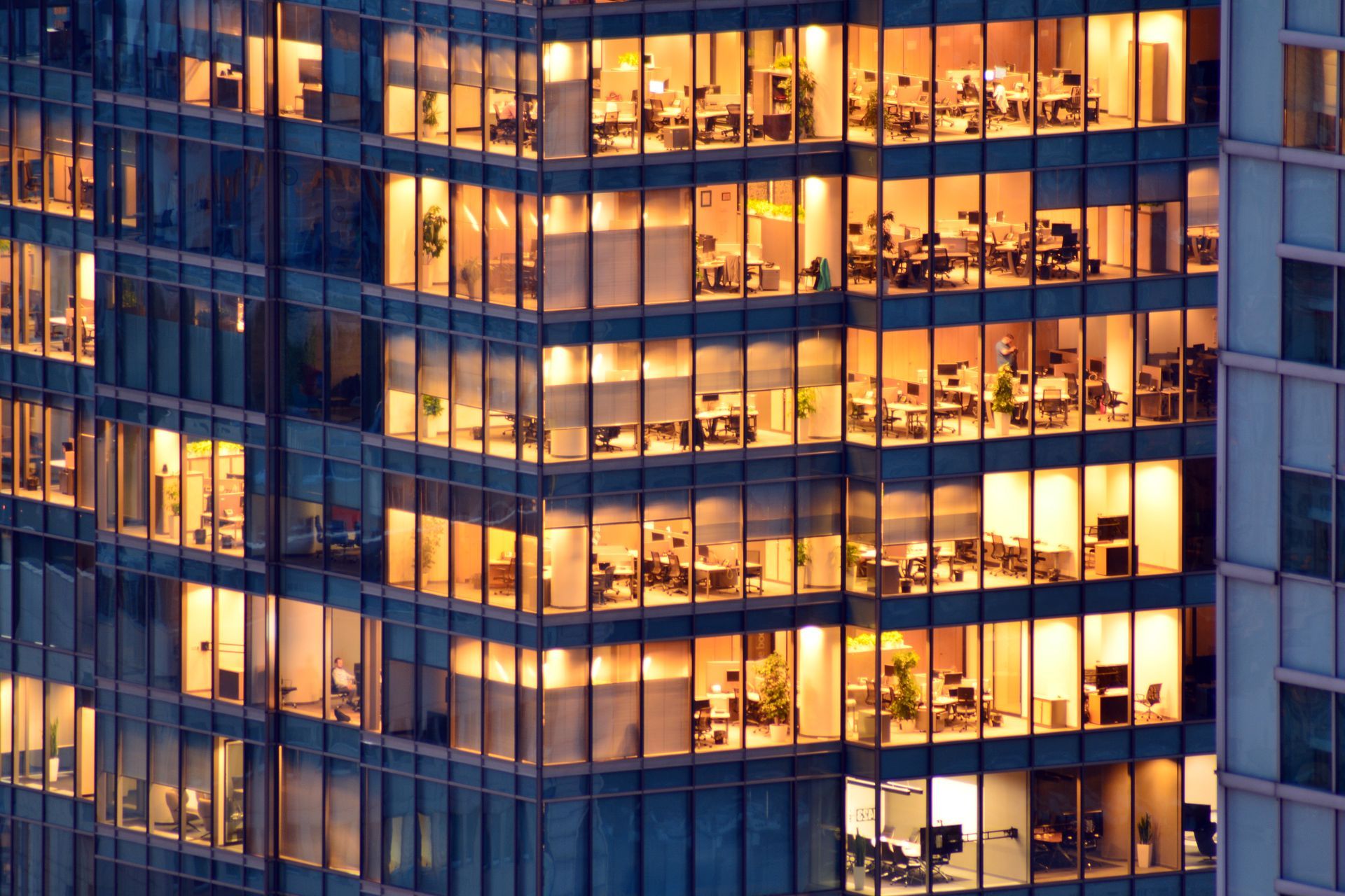 A tall building with lots of windows is lit up at night