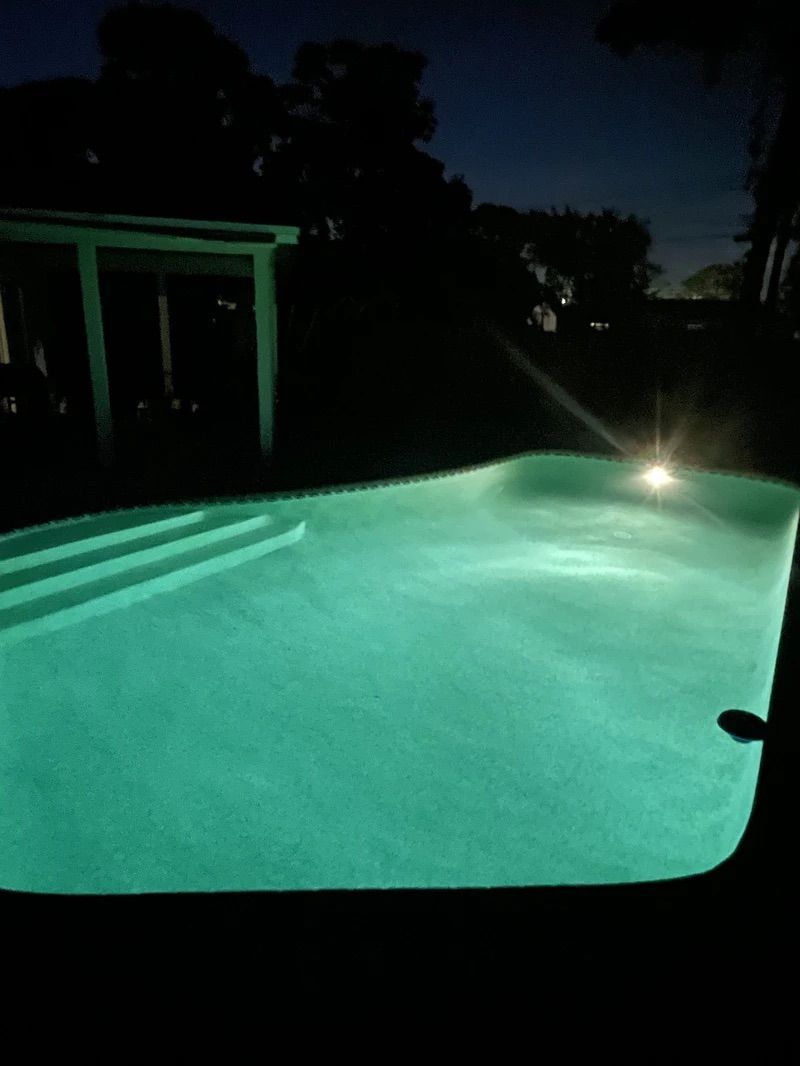 A large swimming pool is lit up at night.