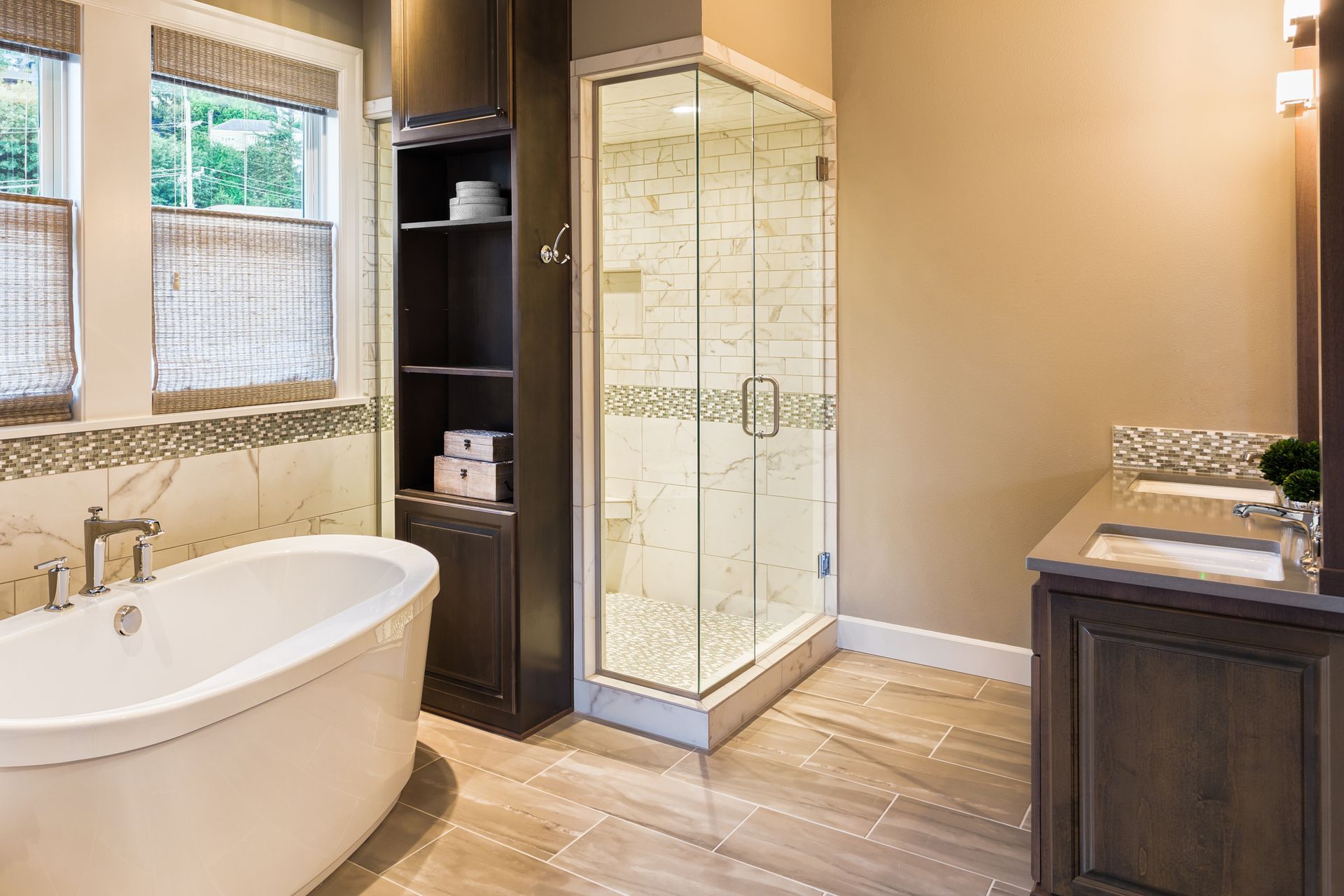 Large furnished bathroom in luxury home with tile floor, fancy cabinets, large mirror, shower, and bathtub.