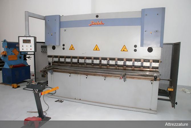 Grande pressa piegatrice industriale in metallo in un'officina, con telaio grigio-blu e segnali di avvertimento gialli.