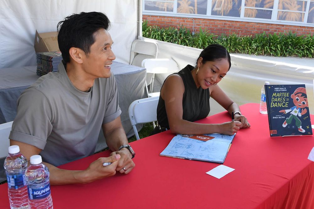 Two authors sign their new book.