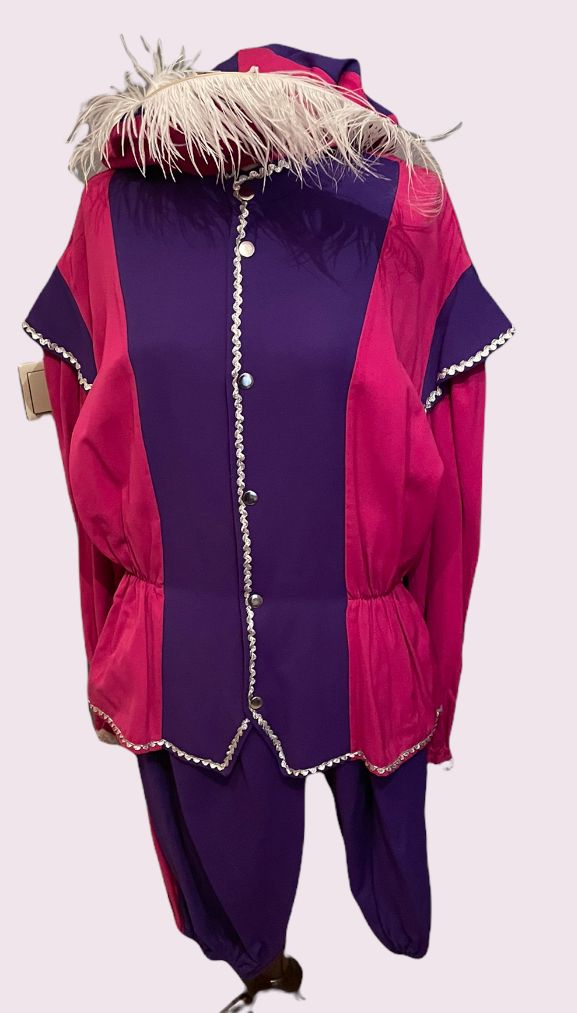 Kleurrijk roze en paars kledingstuk met bontrand, wijde mouwen en losse broekspijpen op een witte achtergrond.