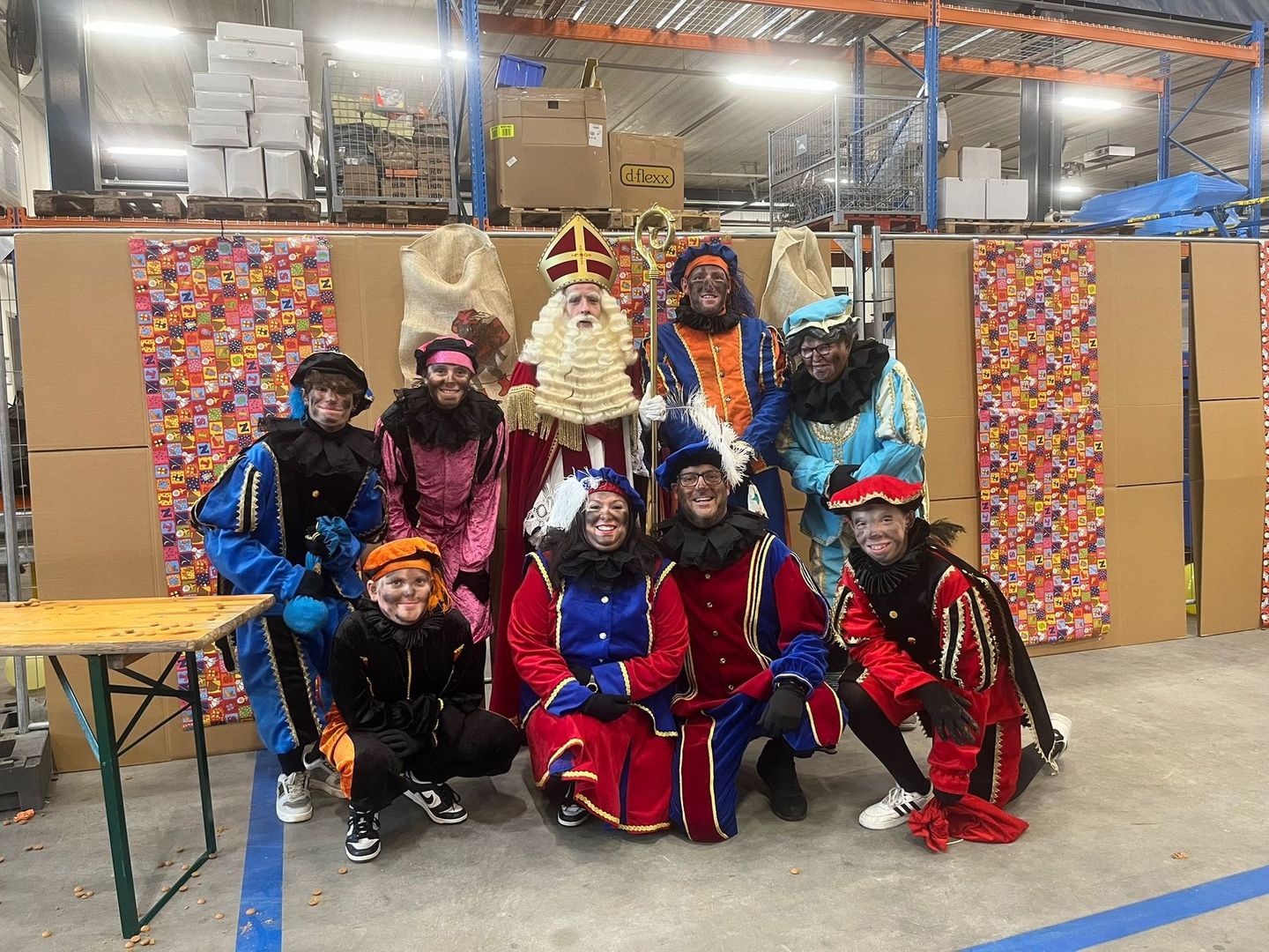 Een groep in kleurrijke kostuums poseert binnen tijdens een feestelijk evenement