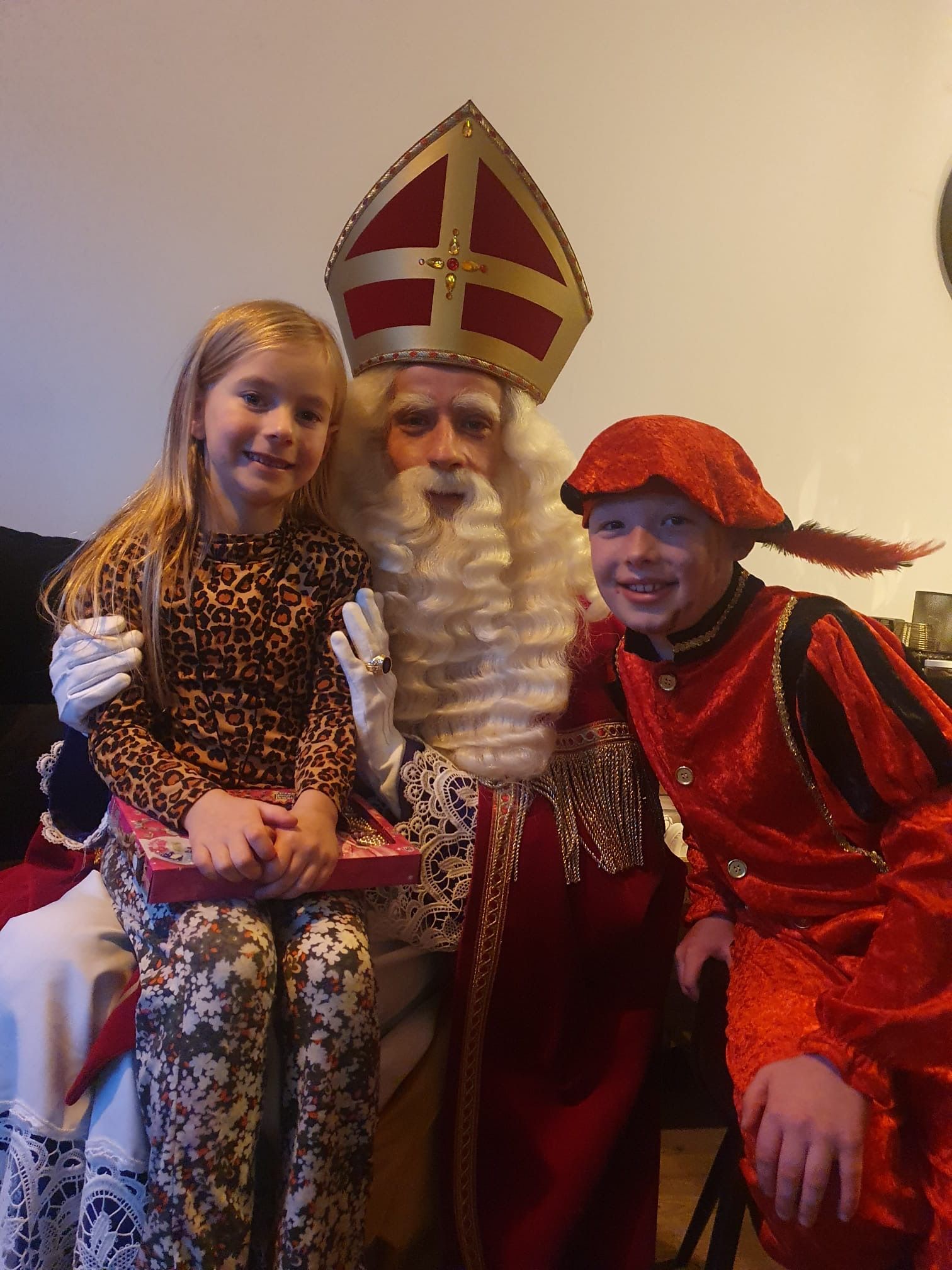 Kind en volwassene in feestelijke kostuums poseren met de kerstman tijdens een kerstevenement.