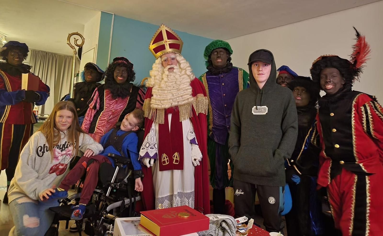 Een groep poseert binnen met een persoon verkleed als kerstman en feestelijke kerstversieringen.