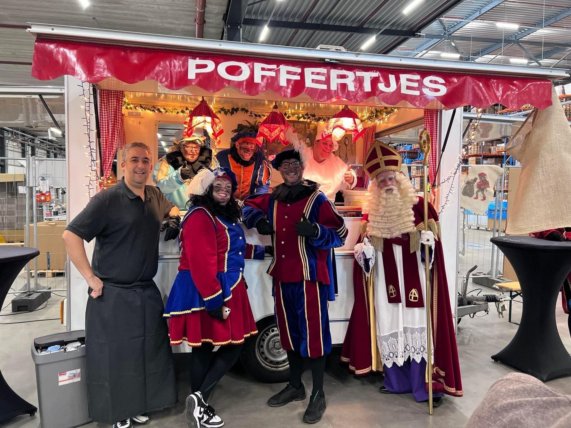 Een kraam met mensen in kleurrijke kostuums onder een rood 