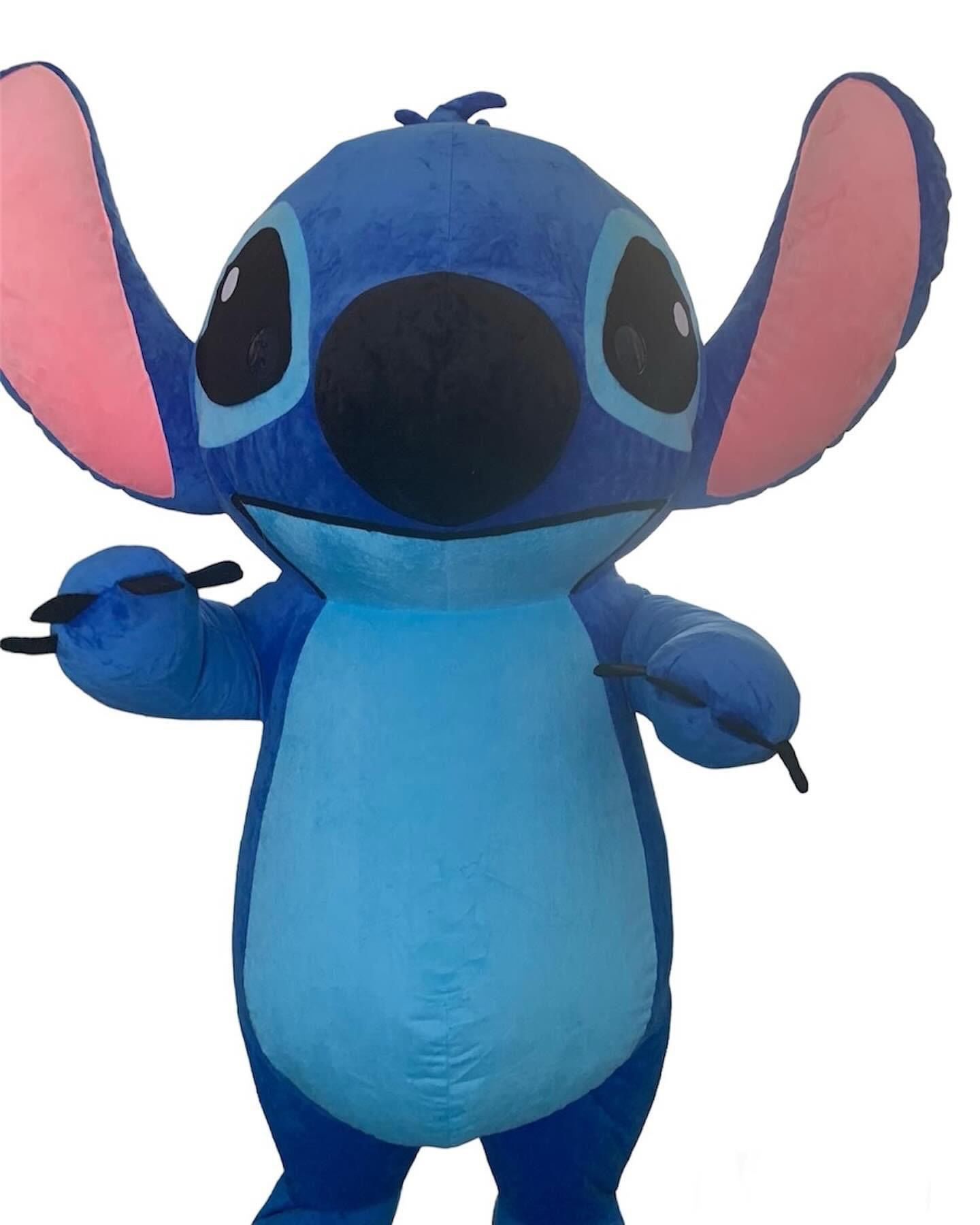 Blauwe Stitch pluche knuffel met roze binnenkant van de oren, kijkt naar voren en houdt één hand omhoog.