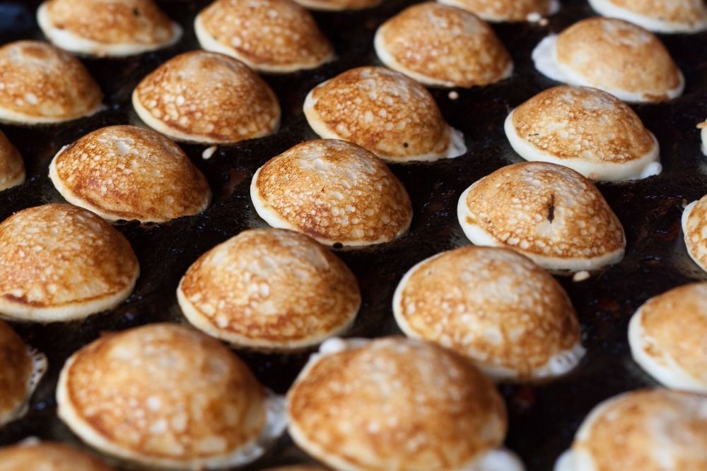 Rijen goudbruine minipannenkoekjes die op een bakplaat worden gebakken.