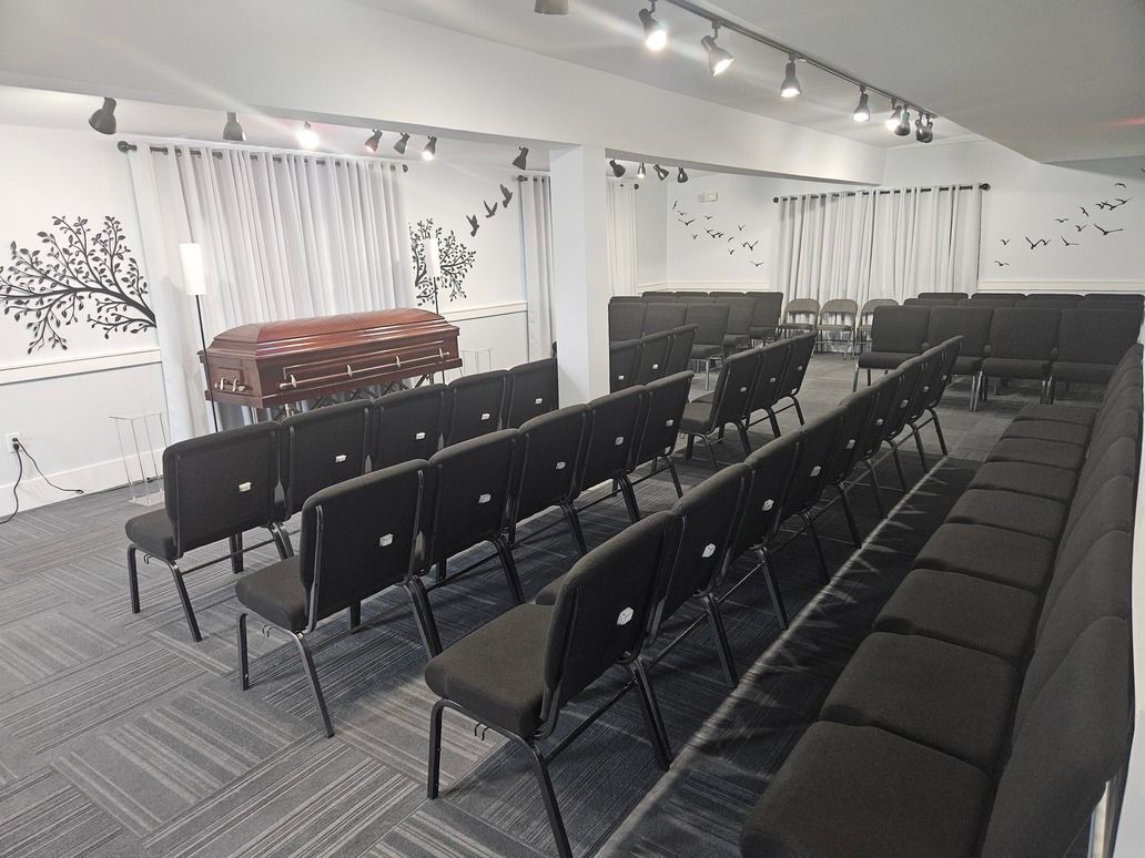 Empty event hall with rows of black chairs, a lectern, and white curtains along the wall.