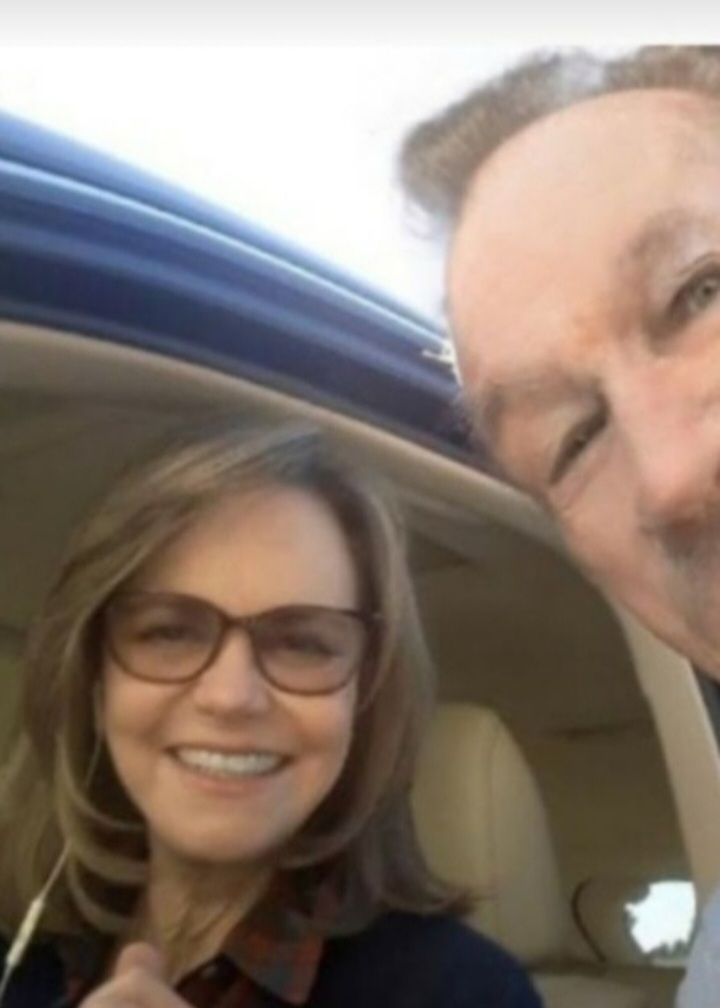 A man and a woman smile closely together for a selfie inside a vehicle.