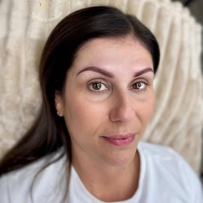 Close-up portrait of a woman with dark hair in a white top against a light textured background