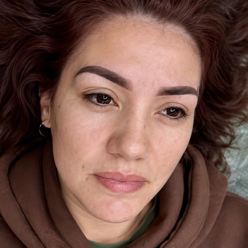 Close-up of a person with short brown hair wearing a brown hoodie, looking slightly downward