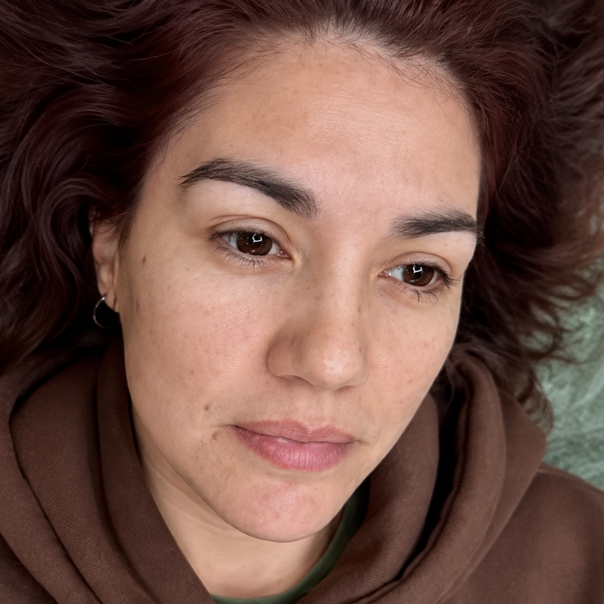 Close-up of a person in a brown hoodie, looking down with a neutral expression.