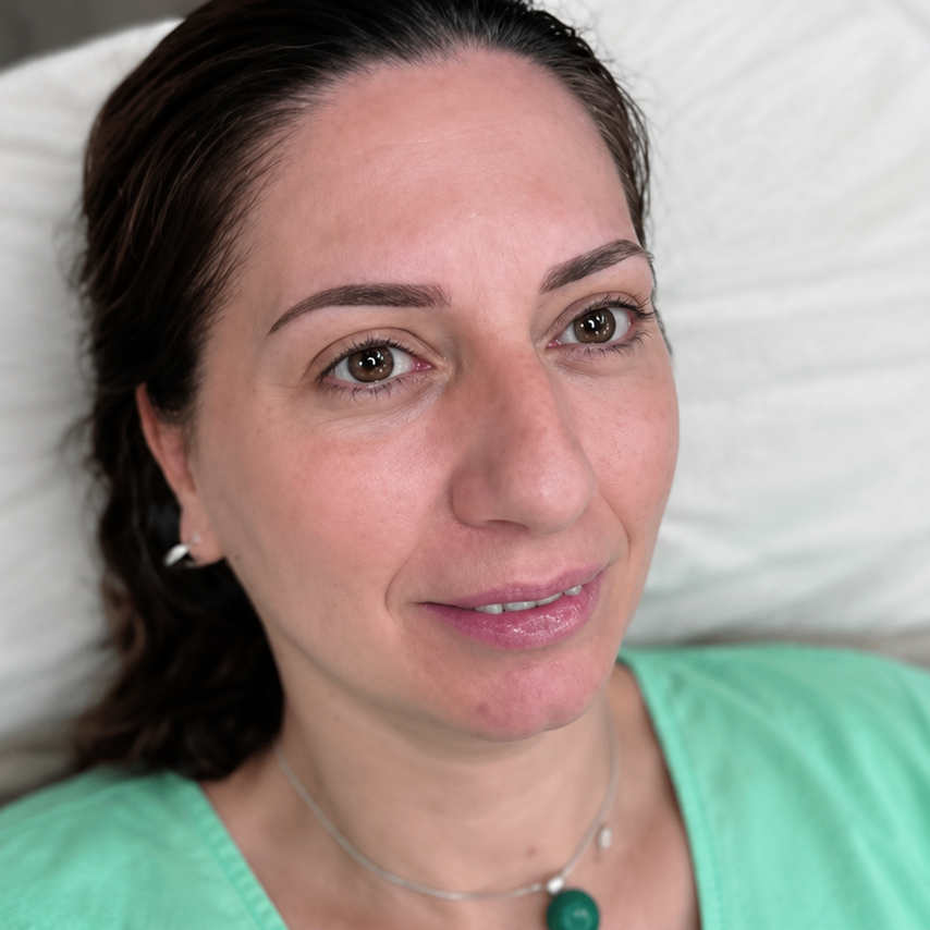 Close-up portrait of a woman with dark hair wearing a mint green top and a slight smile