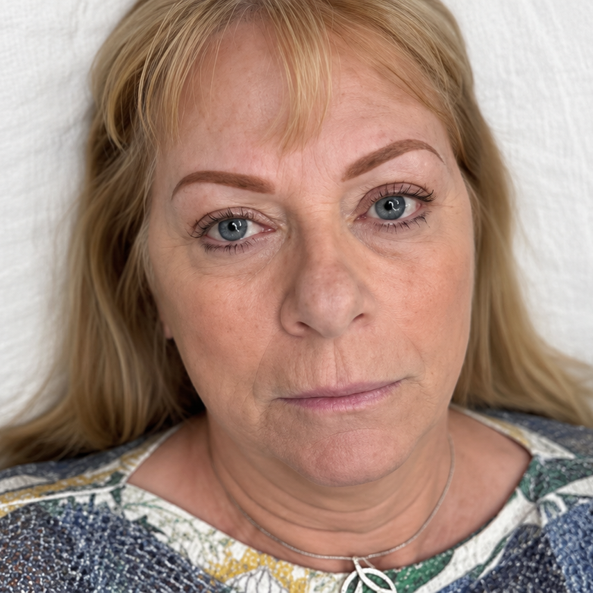 Close-up portrait of a woman with blonde hair, neutral expression, wearing a patterned top
