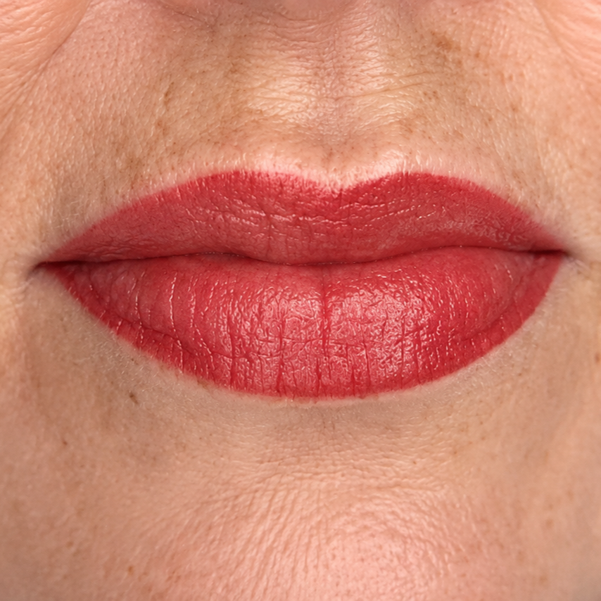 Close-up of lips with matte red lipstick on a neutral skin background