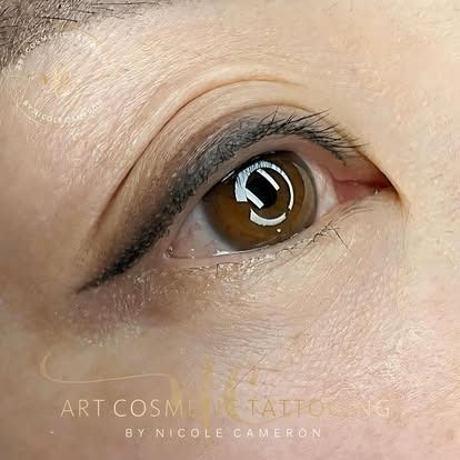 Close-up of a brown eye with black eyeliner and mascara, showing a glossy reflection