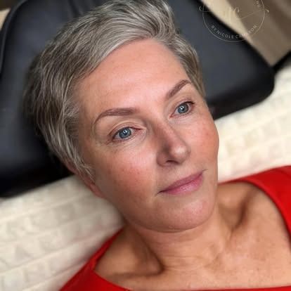 Close-up of a person with short gray hair reclining on a chair, wearing a red top and looking off-camera