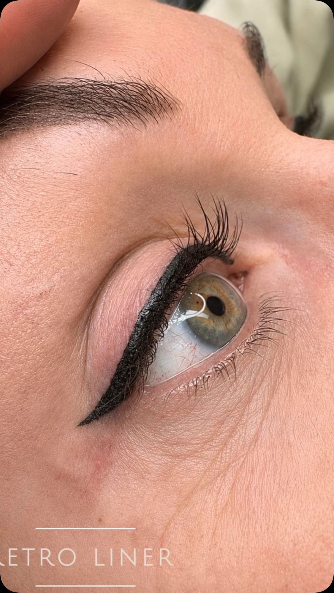 Close-up of an eye with bold black winged eyeliner and groomed eyebrow on light skin