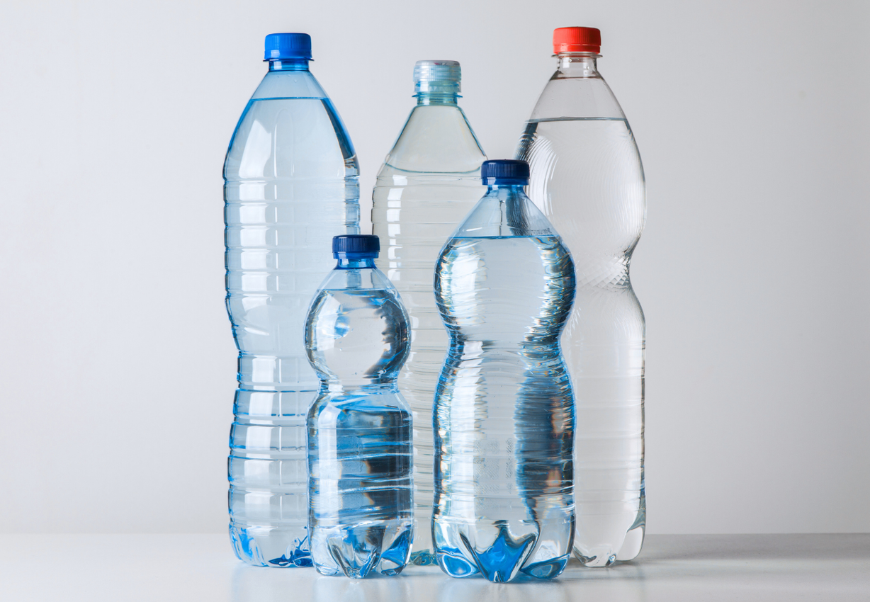 Five clear plastic water bottles with different colored caps.
