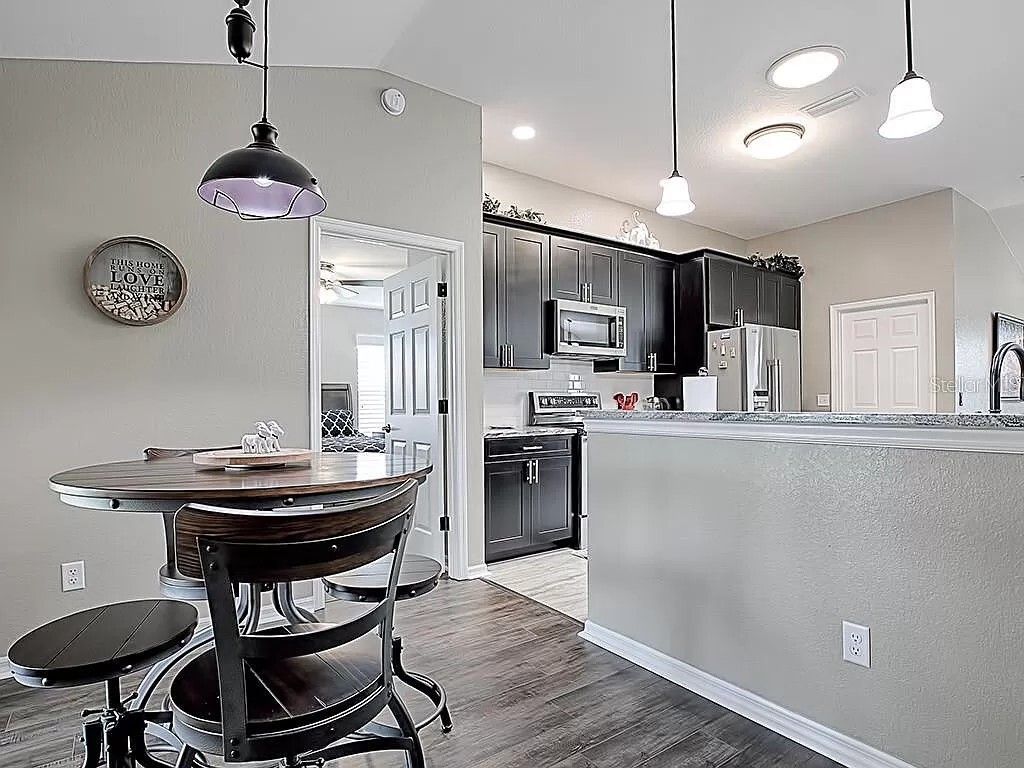 Kitchen with a round table and stools, dark cabinets, and stainless steel appliances.