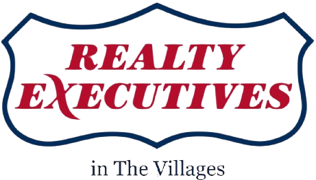 Logo for Realty Executives in The Villages: Red text on a blue, shield-shaped border.