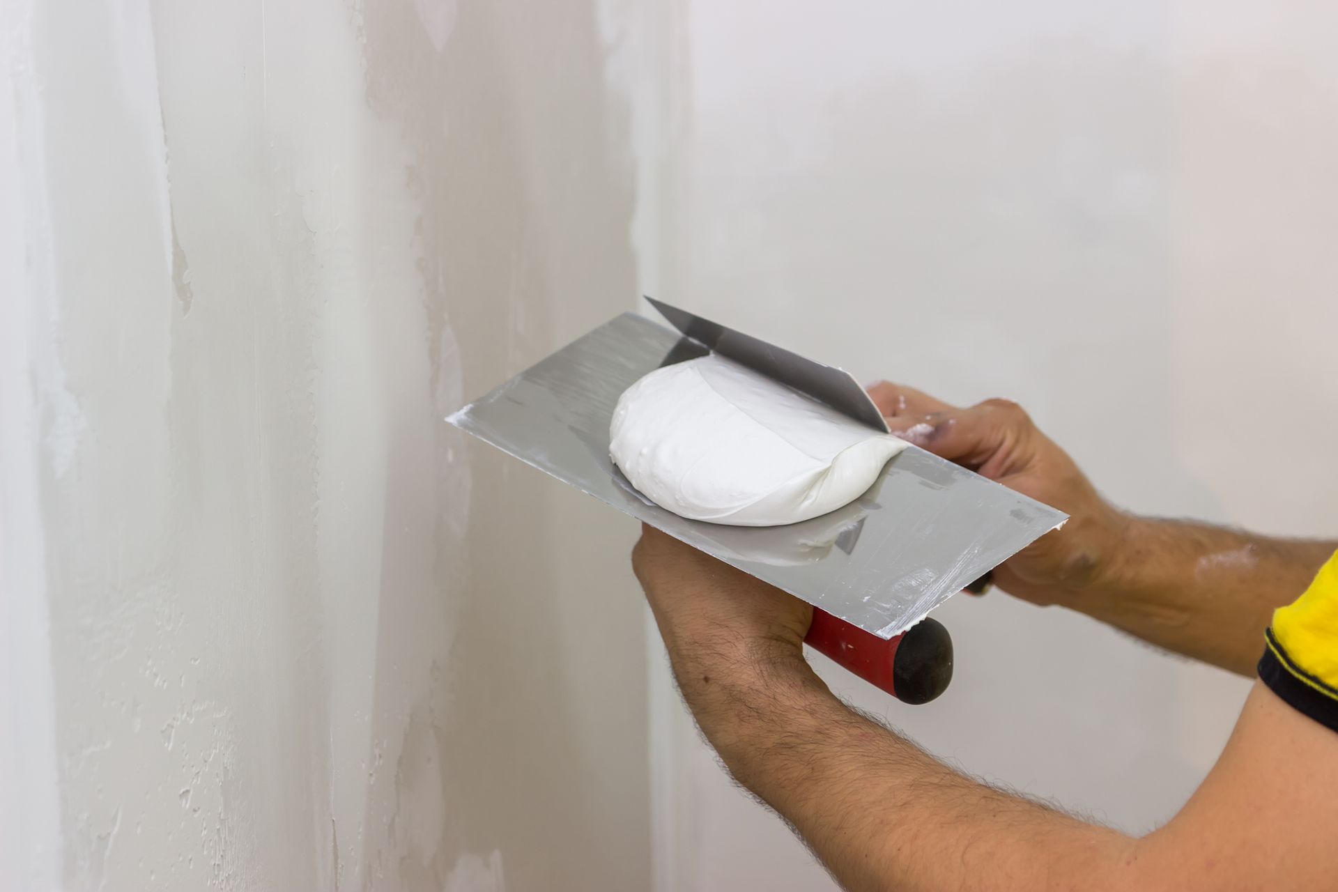 A man is plastering a wall with a trowel.