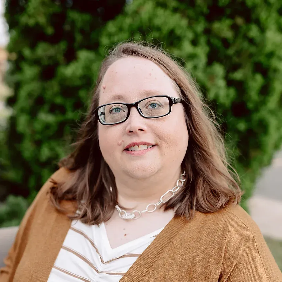 A woman wearing glasses and a striped shirt is smiling for the camera.