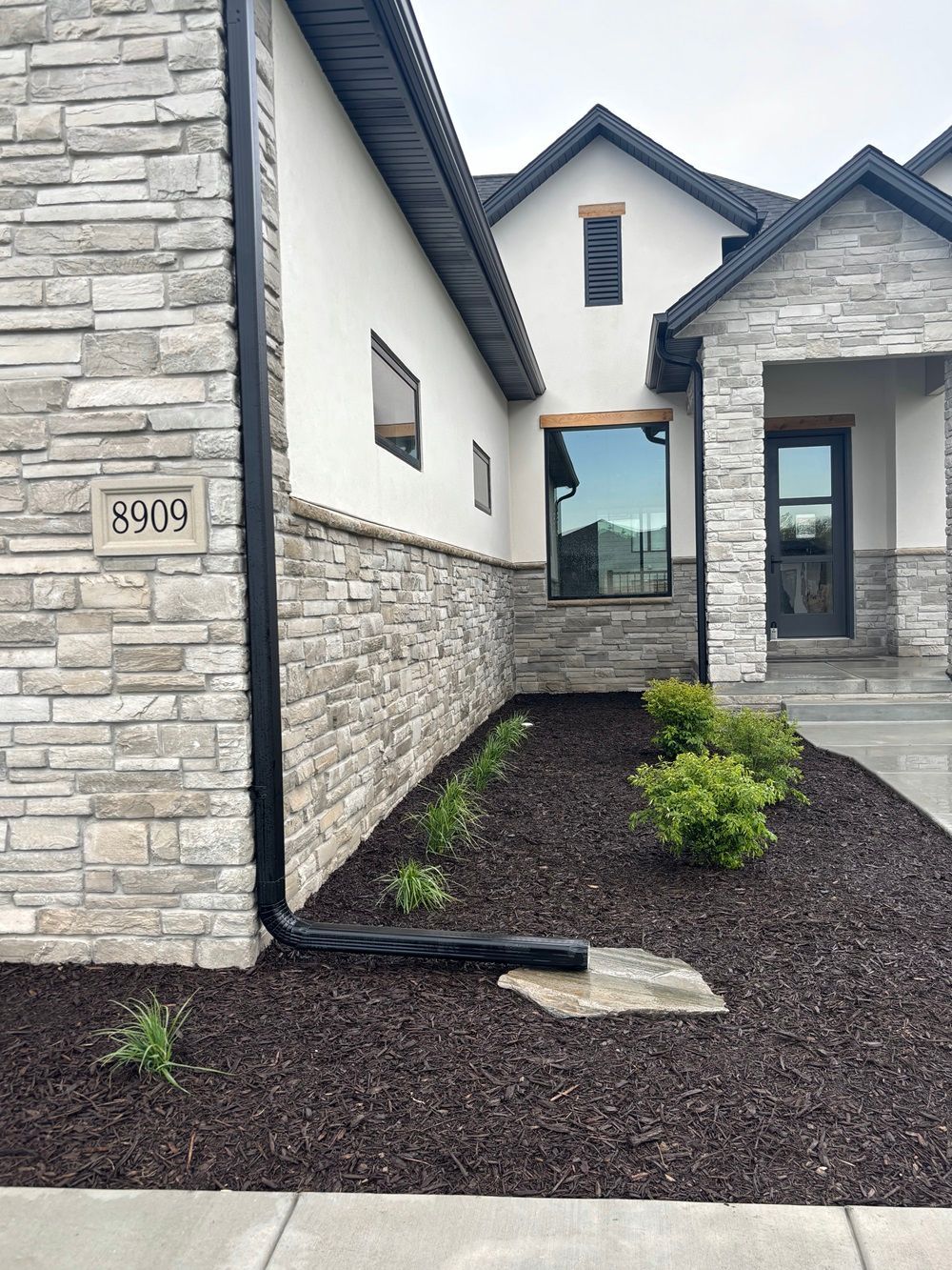 House With Stone, White Siding, And Landscaped Yard
