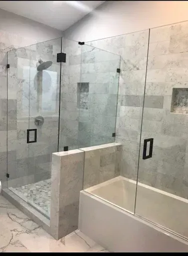 Modern bathroom with a glass-enclosed shower, a built-in bathtub, and gray-toned marble tiling.