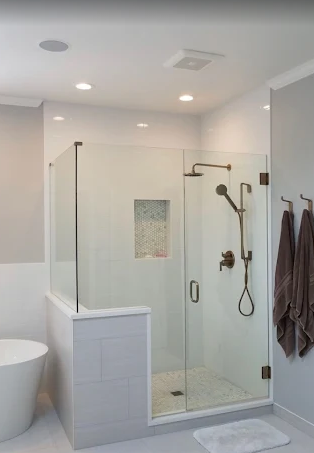 A modern bathroom featuring a glass-enclosed shower with bronze fixtures, tiled walls, and a separate soaking tub.
