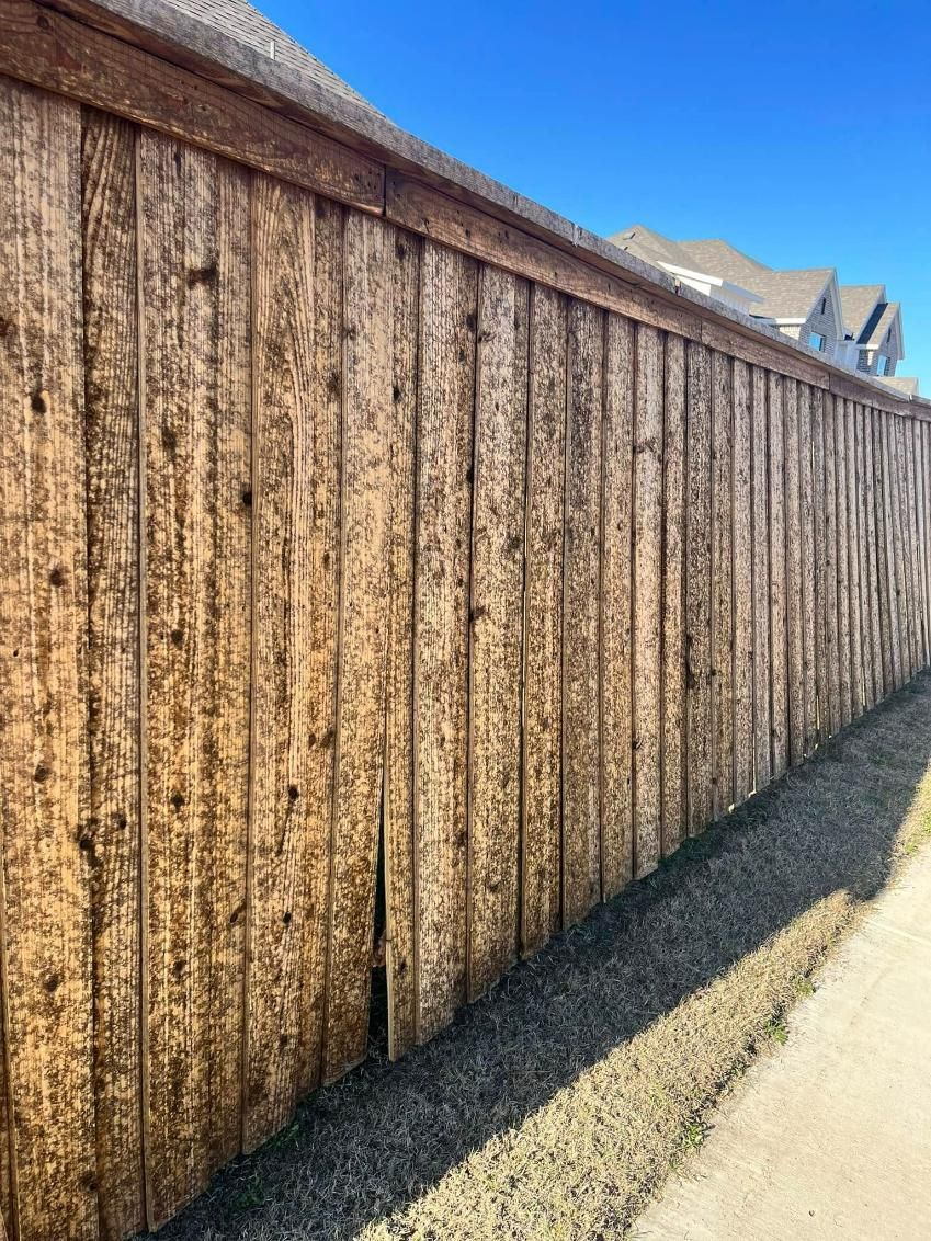Wooden fence, weathered and vertical, against a clear blue sky.