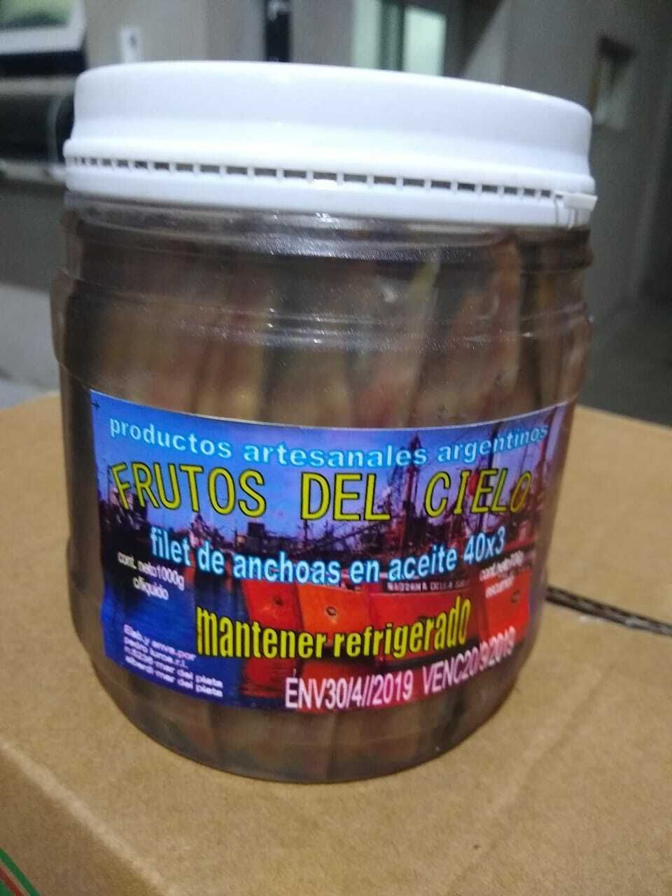Un frasco de mariscos en escabeche con la etiqueta “Frutos del Mar” y una tapa blanca sobre una mesa.