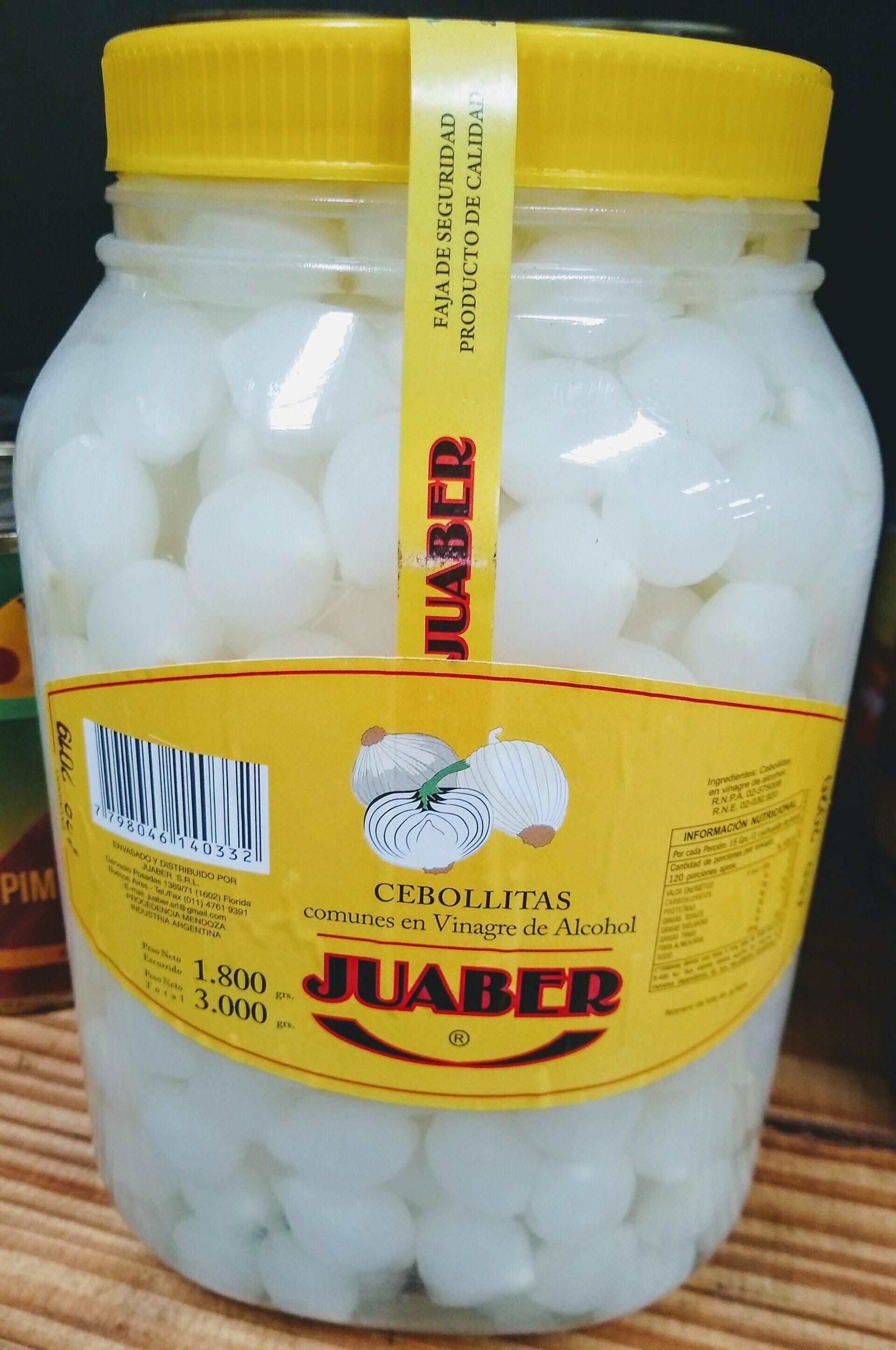 Frasco de cebollas blancas encurtidas con tapa amarilla y etiqueta sobre una superficie tejida.