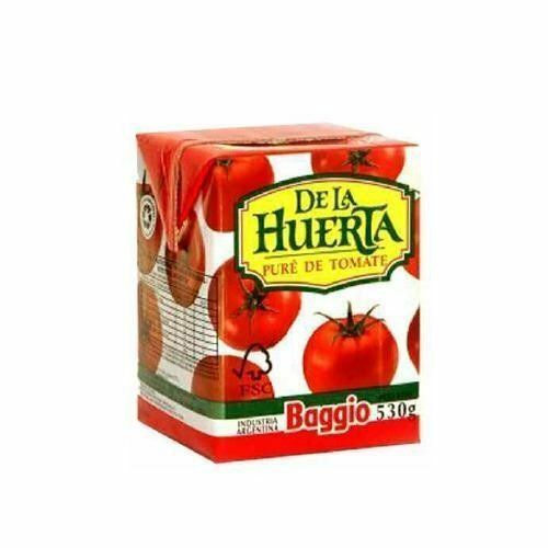 Envase de puré de tomate De la Huerta, rojo y blanco con ilustraciones de tomates y logotipo verde.