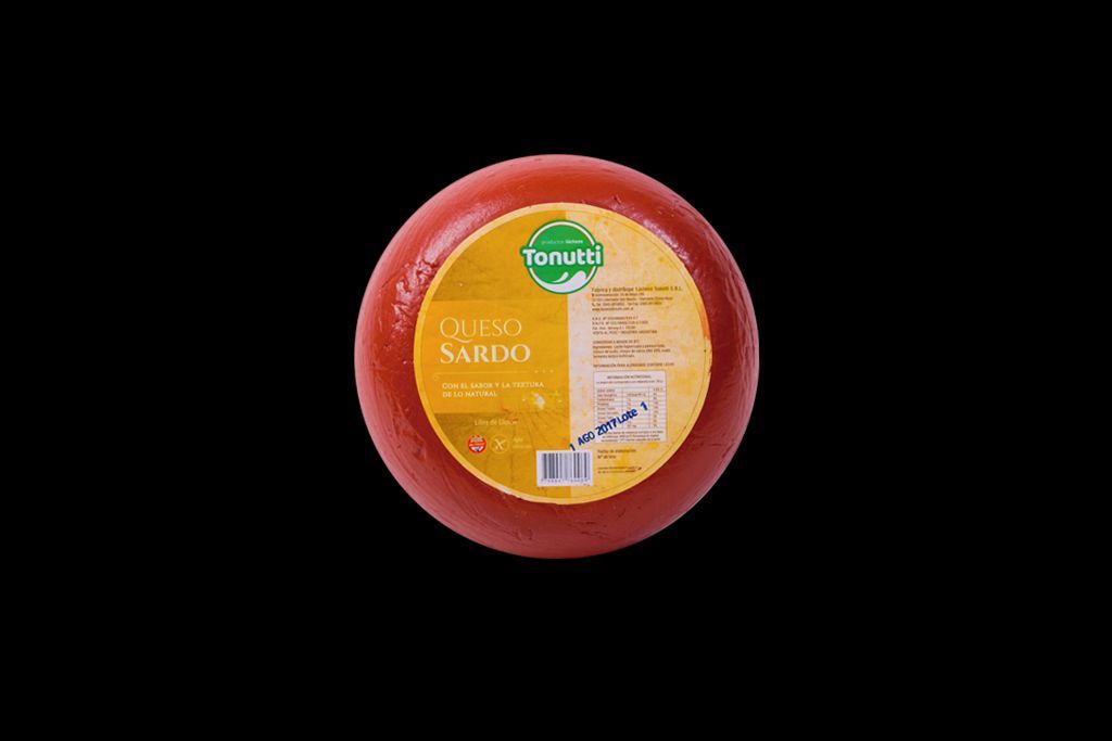 Rueda de queso redonda roja con etiqueta amarilla sobre fondo negro