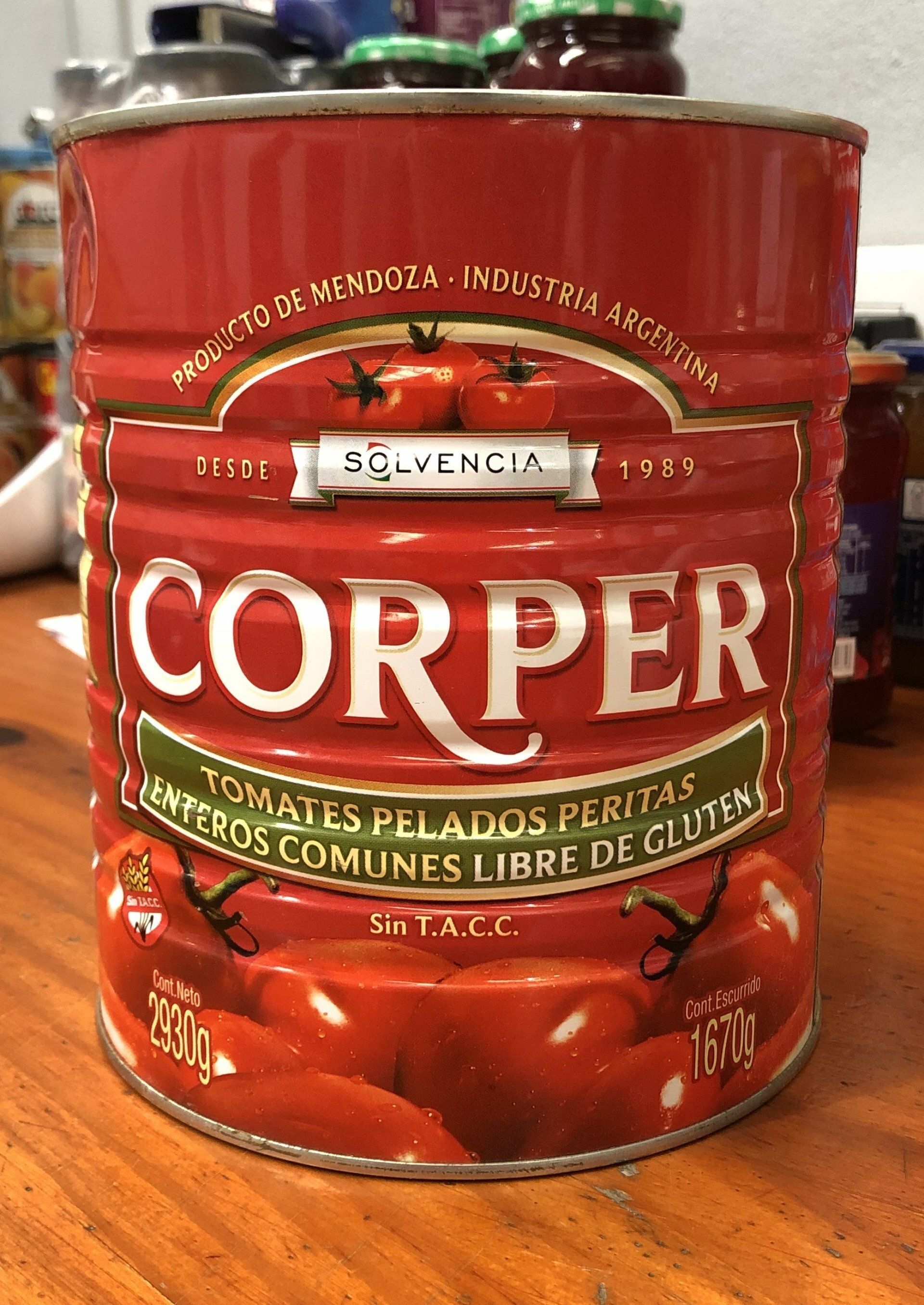 Una lata roja de tomates en conserva CORPER sobre una superficie de madera, con tapa roja y letras blancas.