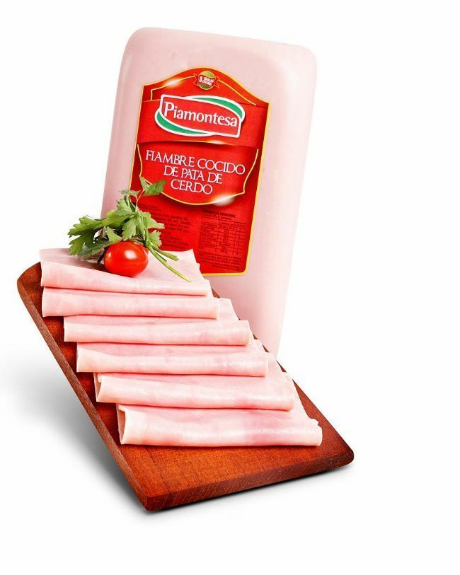 Jamón en lonchas sobre una tabla de madera con un paquete de jamón Pamontesa al fondo.