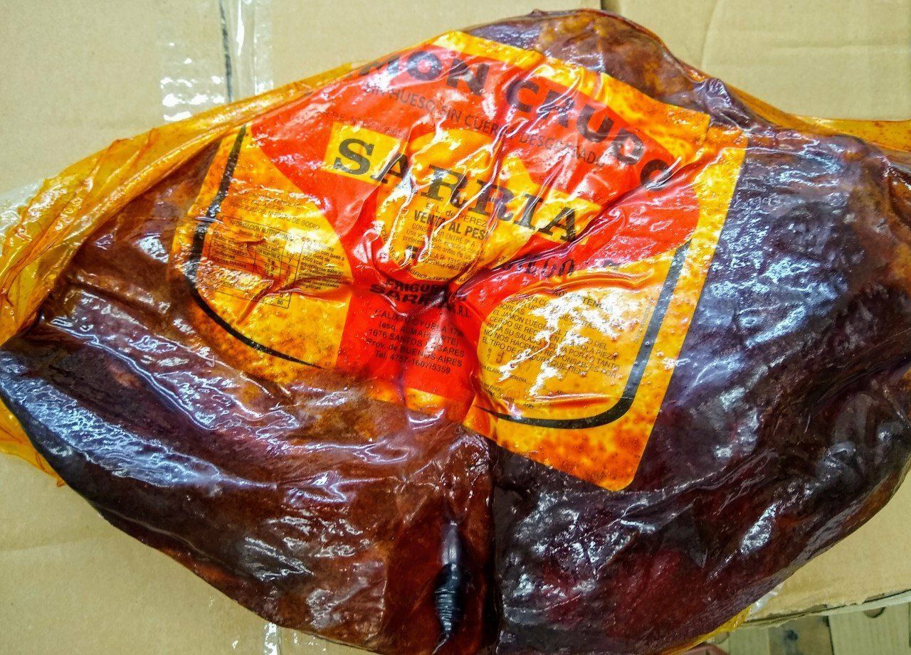 Bolsa o envoltorio de plástico marrón y naranja arrugado sobre un suelo beige.