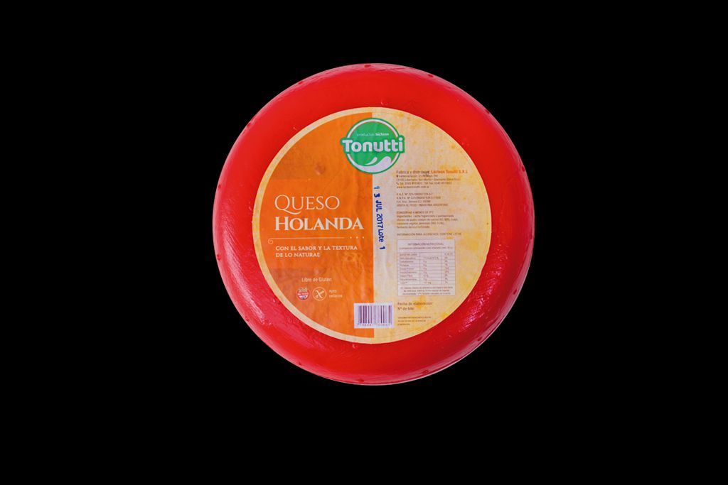 Envase redondo rojo de queso fresco con una etiqueta amarilla sobre fondo negro.