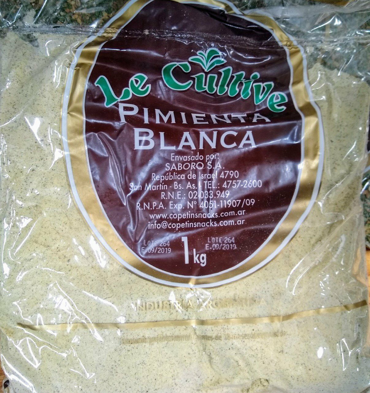 Bolsa de plástico de condimento Le Cultive Pimiento Blanca, etiqueta granate con texto verde y polvo blanco en el interior.