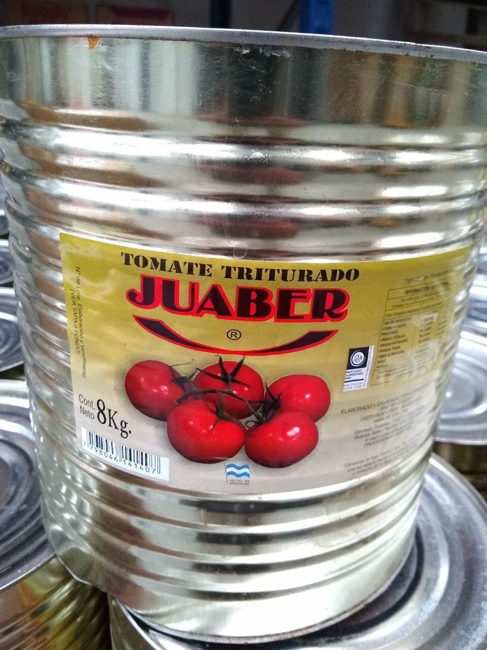 Lata metálica de tomates triturados Juaber con ilustración de tomate rojo y texto en la etiqueta.