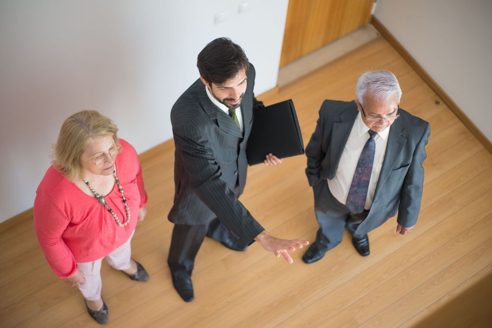 Three business people in suits standing in a hallway, viewed from above, one holding a folder
