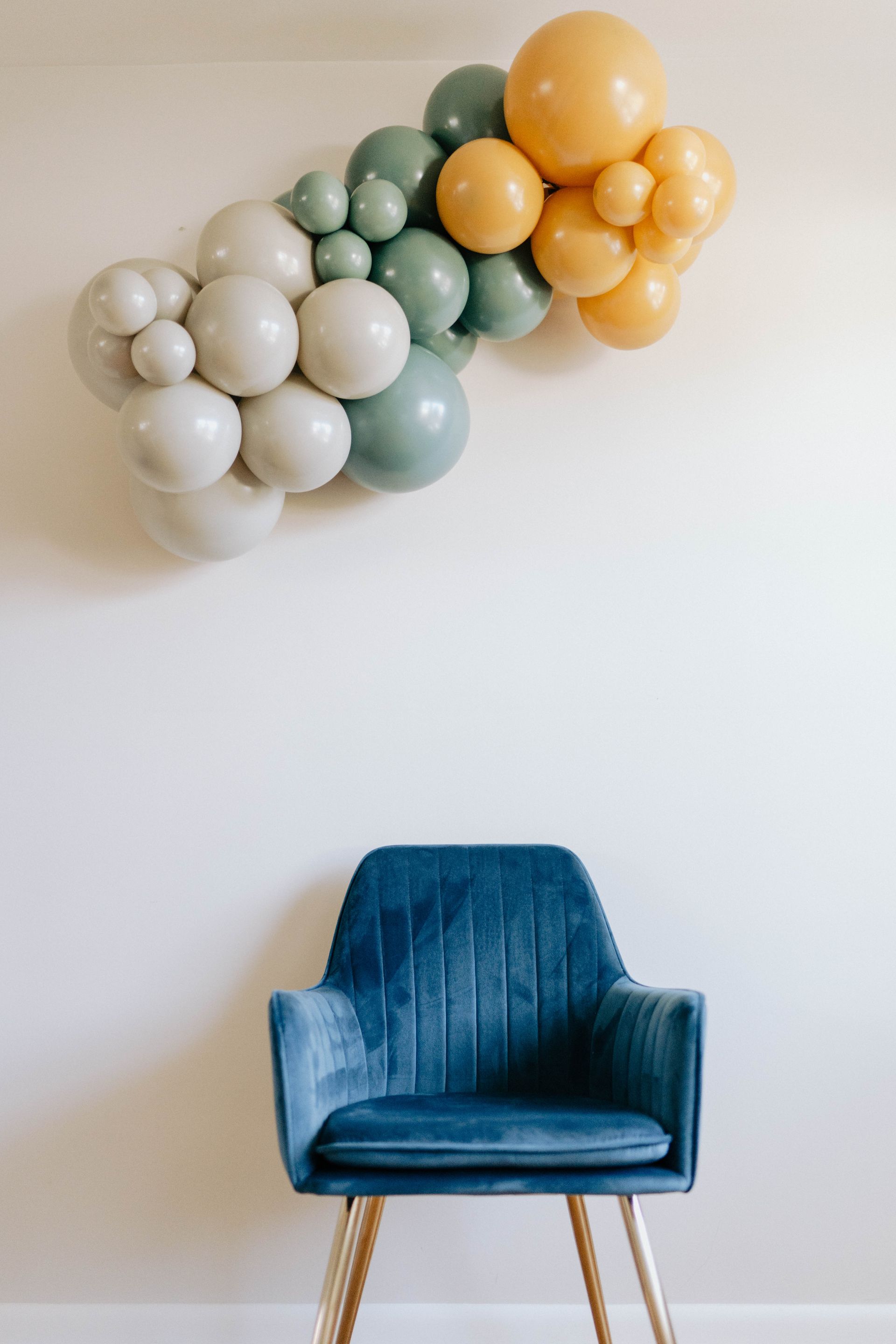 a blue chair is sitting in front of a wall with balloons on it