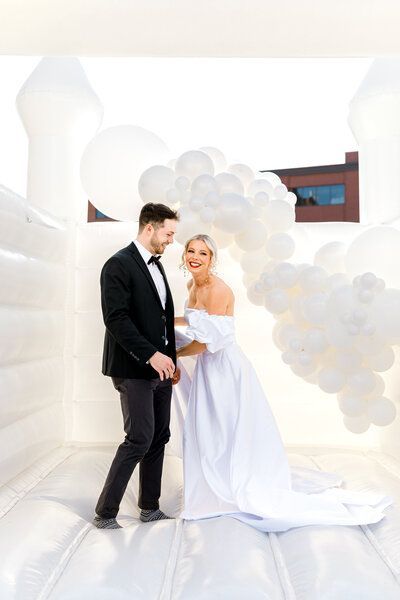 a bride and groom are standing next to each other in a room filled with white balloons