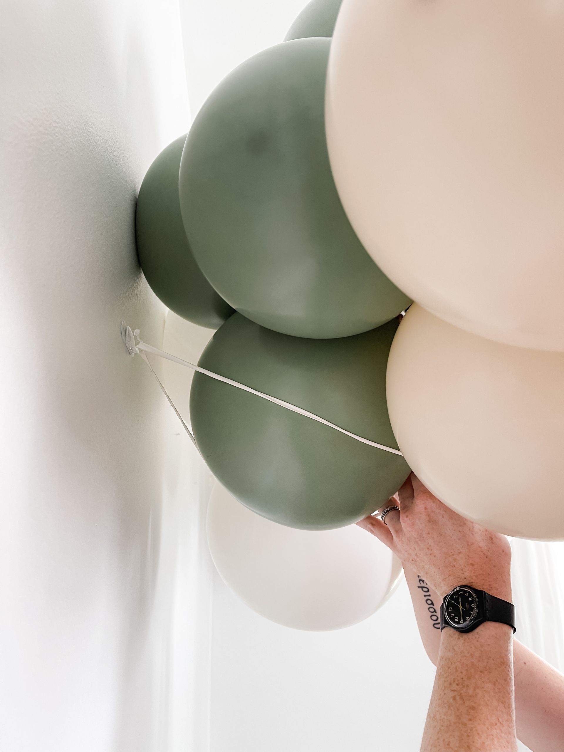 A person is tying balloons to a wall.