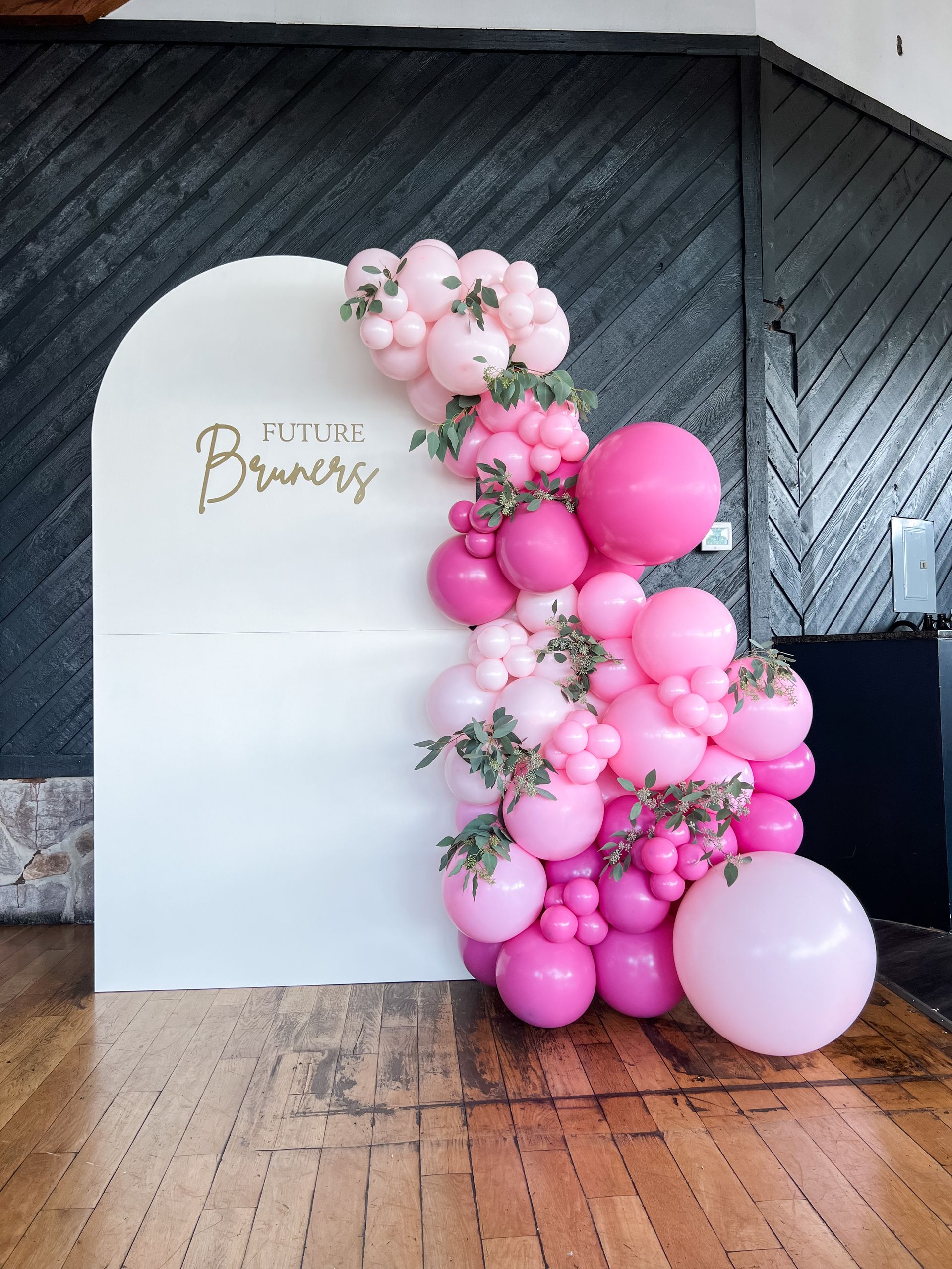 a bunch of pink balloons are sitting on a wooden floor in front of a white wall