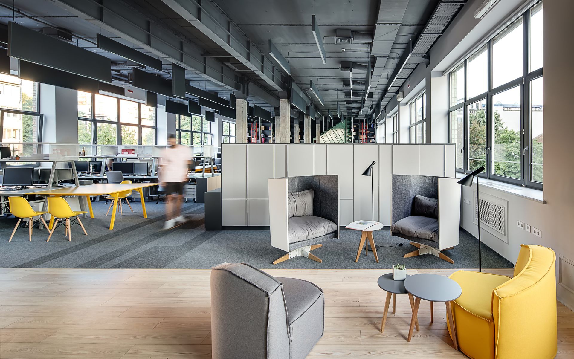A blurred view of an office employee walking through a modern, loft office. A blurred view of an office employee walking through a modern, loft office.