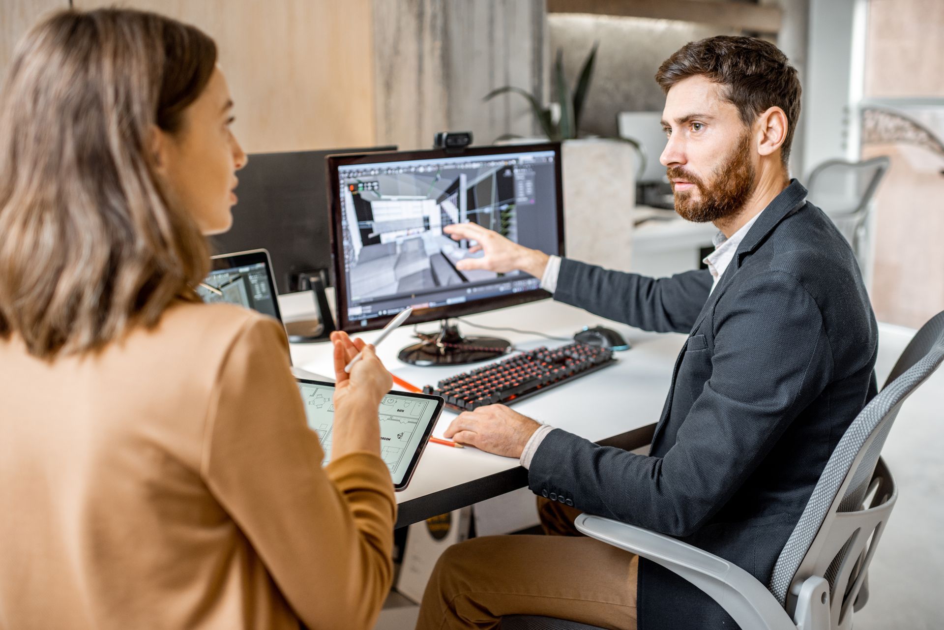 Two creative office employees are making interior designs on a computer and a digital tablet. Two creative office employees are making interior designs on a computer and a digital tablet.