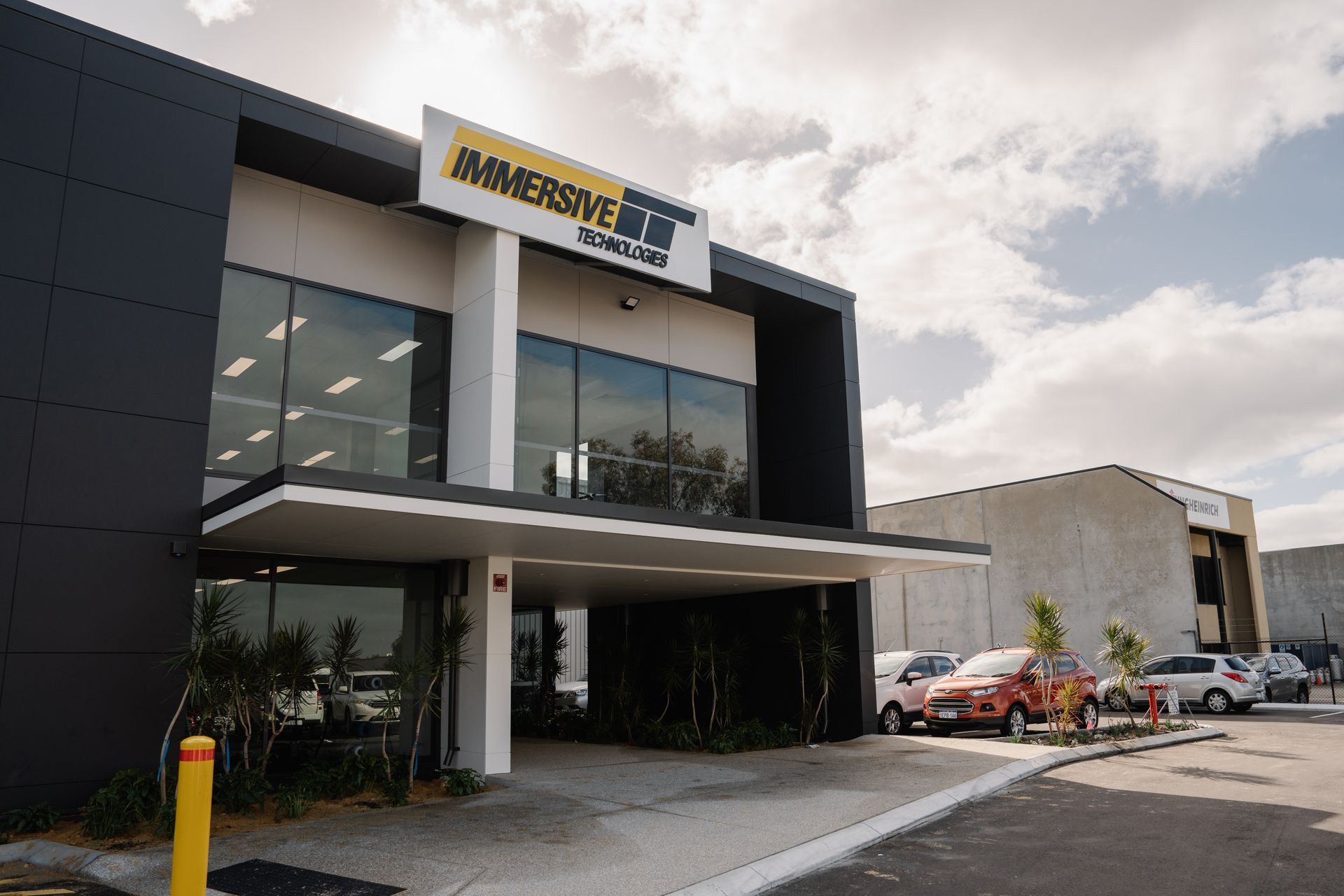 Exterior of Immersive Escapes building with cars parked nearby.